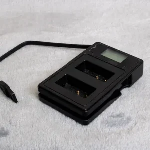 Black dual battery charger with a small screen and attached power cord.